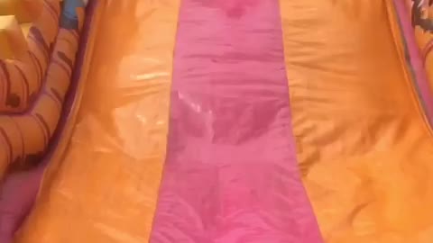 Little kid jumps down yellow and pink slide and hits face