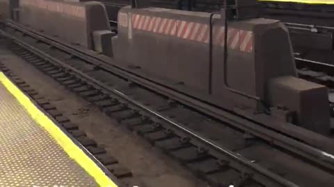 What is happening here lady in white jacket sitting on edge of subway tracks platform