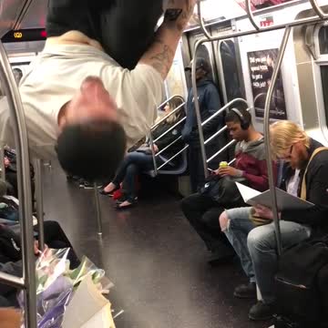Man in white shirt performing on subway train