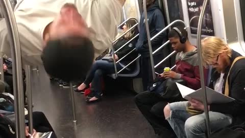 Man in white shirt performing on subway train