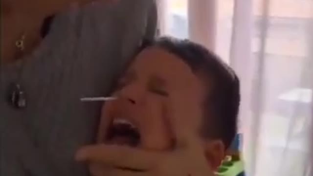 A child in Germany cries sorrowfully from the test swab jammed up his nose by his mother.