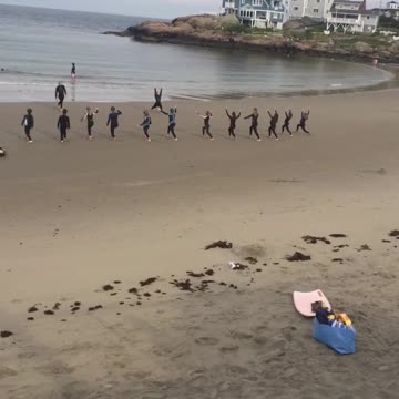 Surfboards laid out on beach surfers doing yoga on sand
