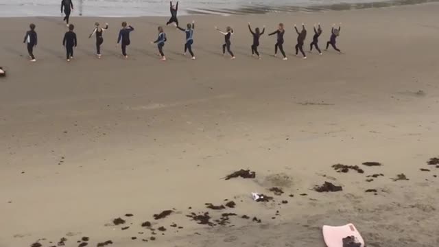 Surfboards laid out on beach surfers doing yoga on sand