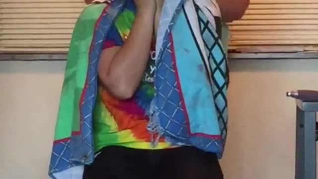 Happy black dog on couch smiling watching his owner in tye dye rainbow shirt get hair done at home