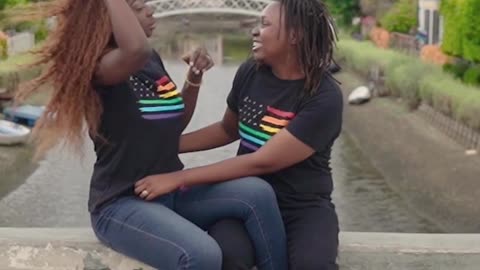 A Couple Sitting On A Bridge Wall