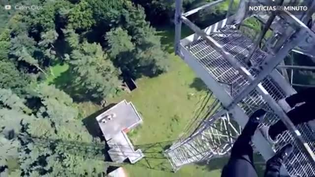 Jovem se pendura em torre de altura impressionante