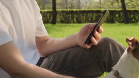 Handheld slowmo tilt up of young man in face mask sitting on green grass in park