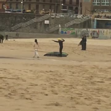 Old guy on sand pretending to paddle and swim in wet suit