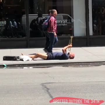 Man plays trumpet on floor of street