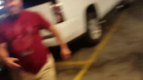 Guy hides between cars and scare friend in red shirt walking by