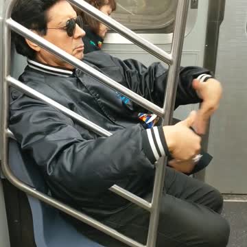 Man waves air into his face with his hands on subway train