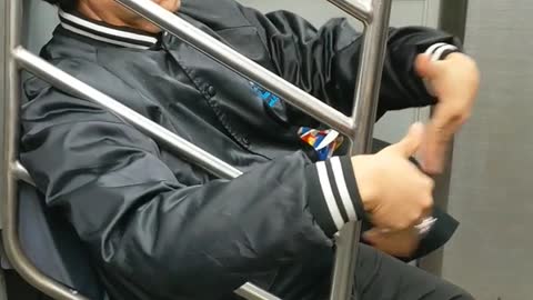 Man waves air into his face with his hands on subway train