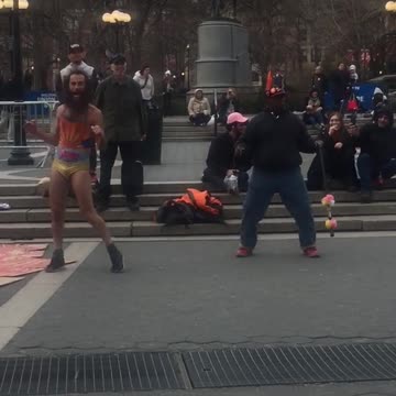 Two crazy guys one in yellow underwear dancing in square