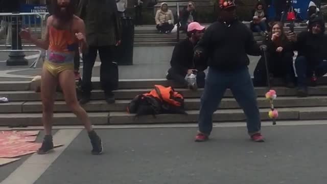 Two crazy guys one in yellow underwear dancing in square