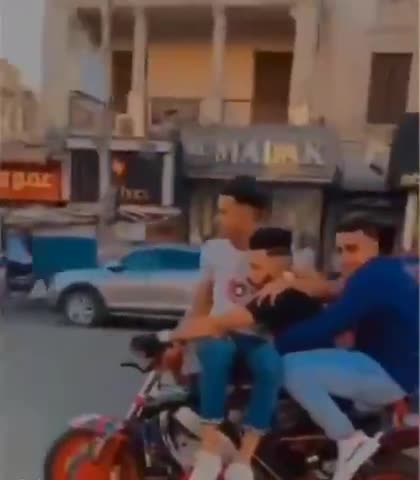 Guy attempts wheelie with 2 of his mates on the bike