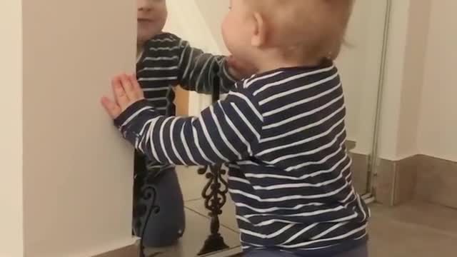 Sweet baby talks to his reflection in the mirror