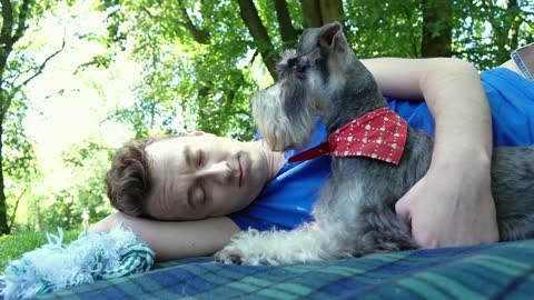 Boy having a nap in the park and lying on the blanket with his cute dog