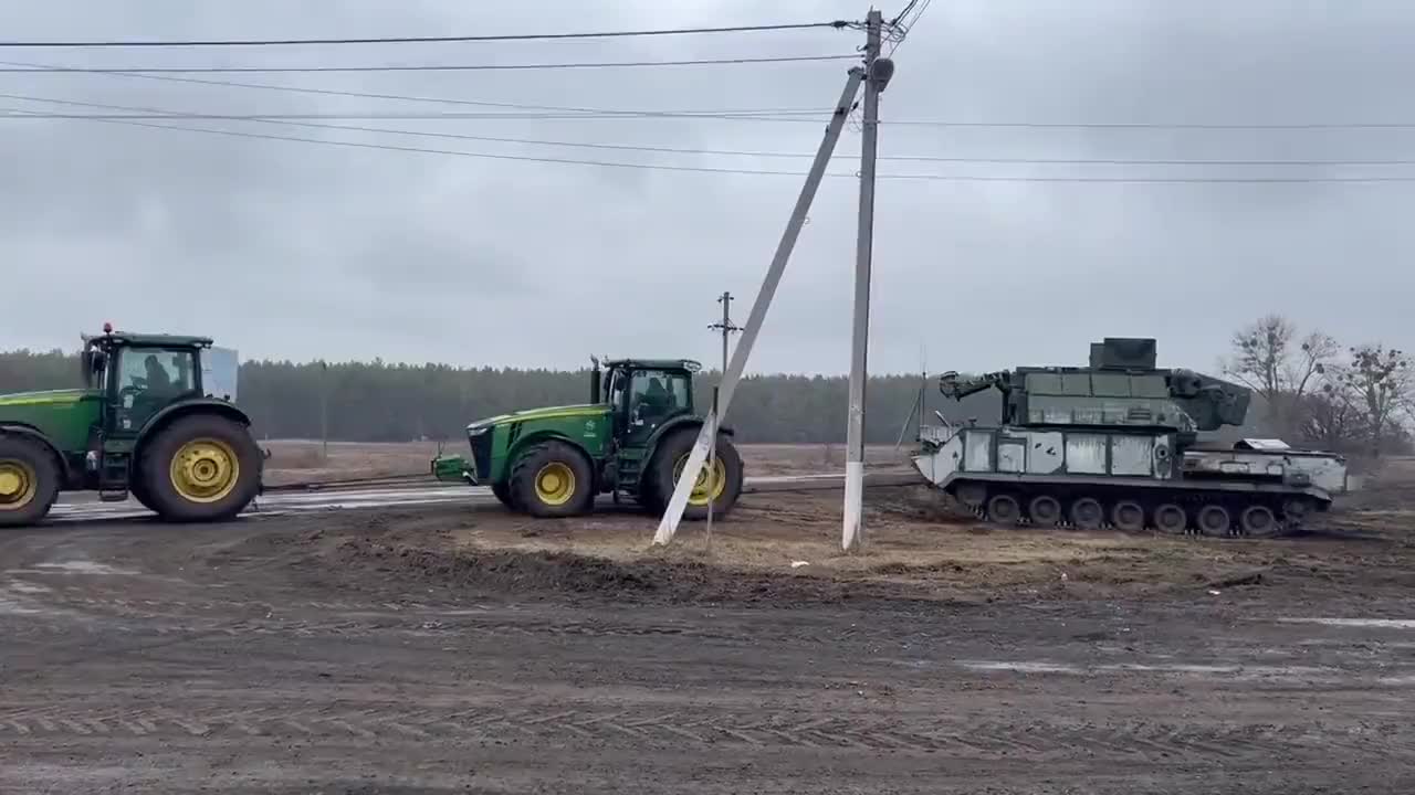 Ukrainian farmers towing an abandoned Russian Tor-M2 short-range air defense system