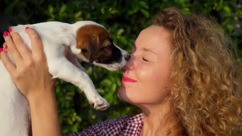 Woman Hugging and Kissing Cute Small Puppy Outdoors