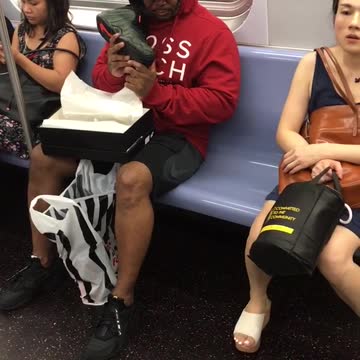 Guy red hoodie subway train smelling new shoe