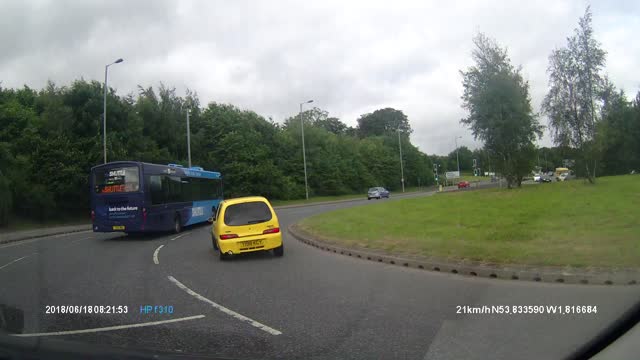 Reckless driver barely passes bus on roundabout