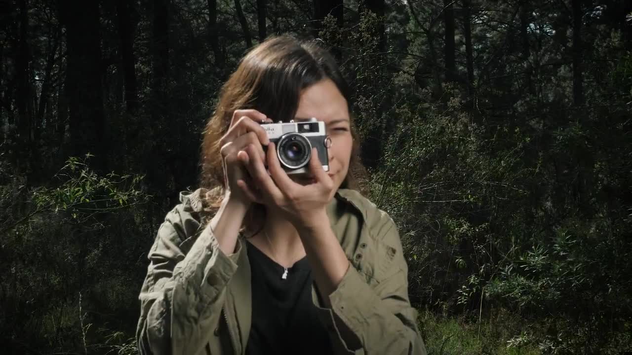 Woman taking photos in the woods with vintage camera