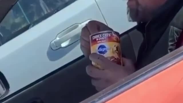 Man is driving car eating a can of dog food