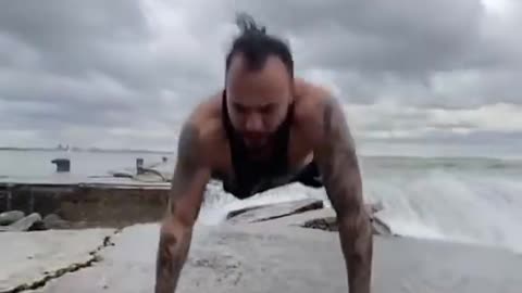 Bodybuilder Does Exercises on Pier While Strong Waves Wash It Amidst Storm