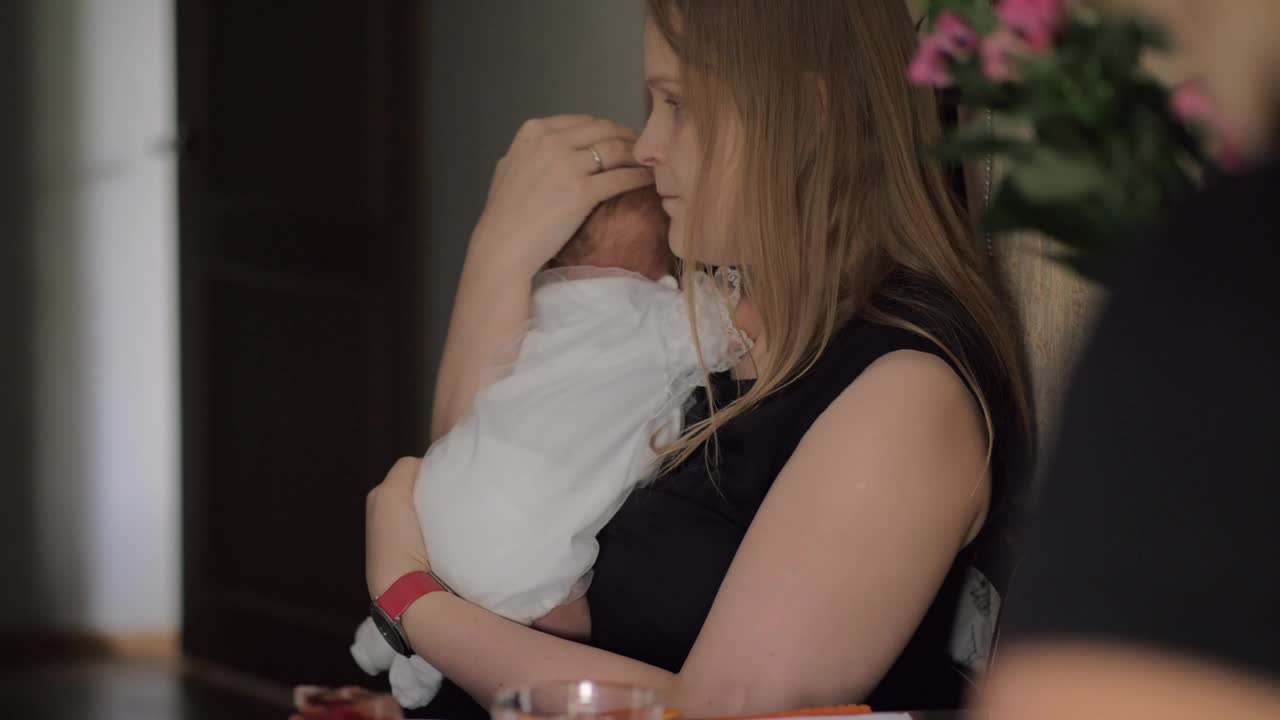Woman eating breakfast while holding her baby