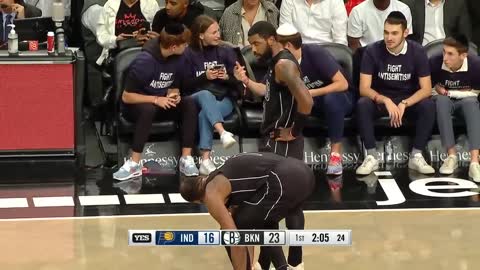 Kyrie Irving standing in front of courtside fans wearing "Fight Antisemitism" t-shirts