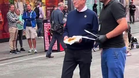 Bill Gates seen doing a photo shoot of himself eating a hot dog in Times Square.