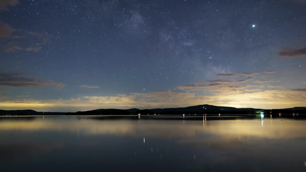 Night sky with stars at a calm lake, time lapse