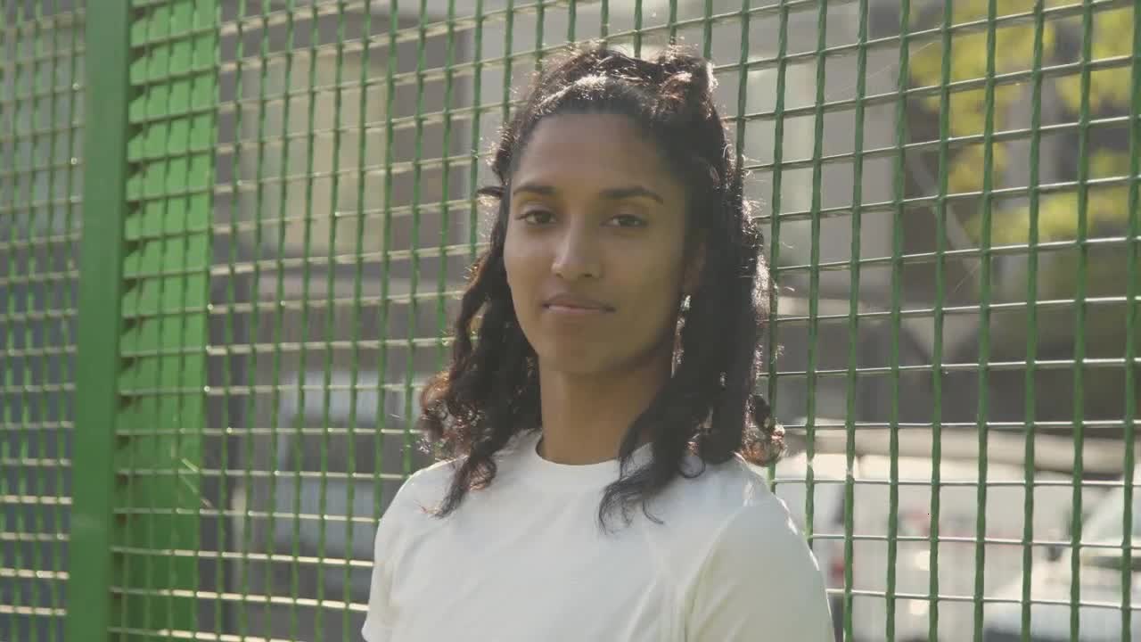 Portrait Of Young Woman Against Fence