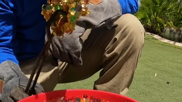 Pouring molten metal into water beads to make a sculpture