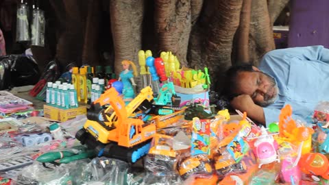 Man sleeping in front of a street toy shop