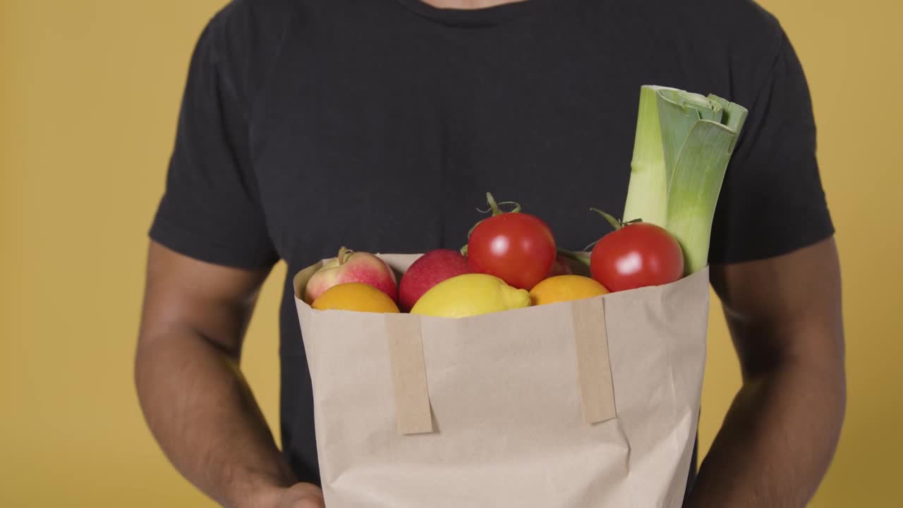 Close Up Shot of Man Holding Bag of Fruit and Vegetables-A close-up shot of a man holding a brown pa