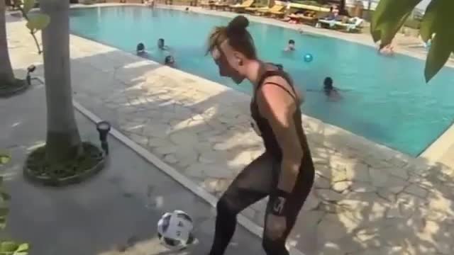 A girl was playing football by herself by the pool