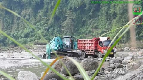 Excavator trucks digging san from the river.