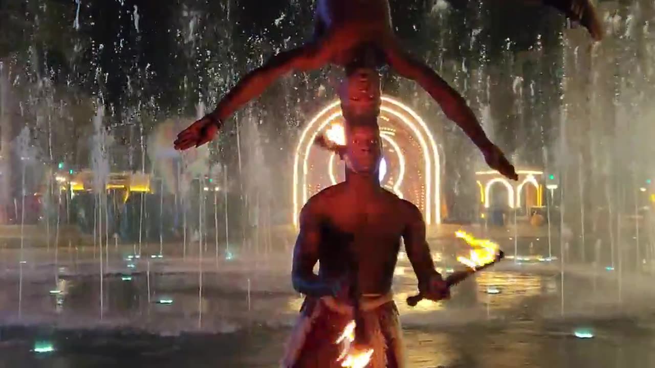 Guy Juggling Fire Clubs While Head Balancing Another