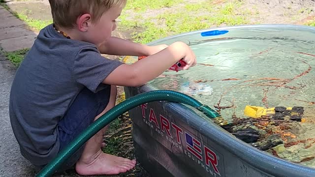 Theo playing and learning about currents in the trough with a sprinkler and rescue vehicles!