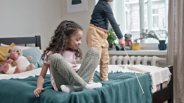 Kids Playing Catch The Bait With Their Cat In The Bedroom