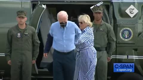 Joe Biden struggles to get his jacket on before dropping his sunglasses