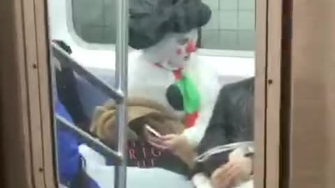 Woman with face paint, dressed in snowman suit on subway train