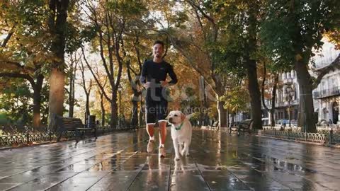 Young black man running with his white labrador dog