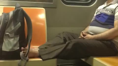 Man sits with no shoes on on subway