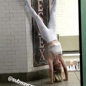 Girl in white doing handstand on subway station