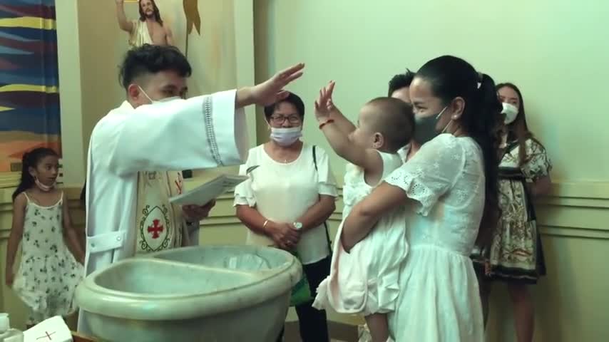 Baby high-fives priest during her own baptism