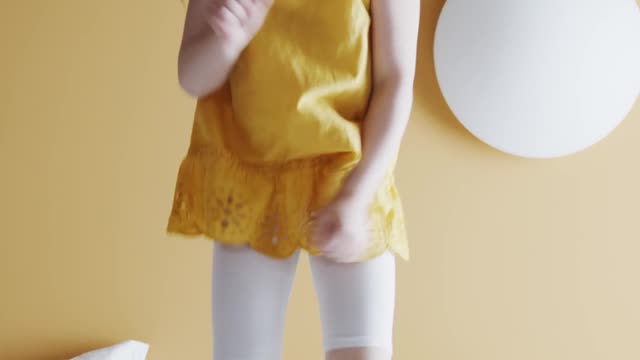 The baby is jumping on the bed
