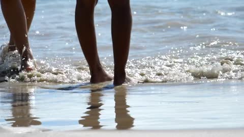 Male and female feet are standing on the sandy beach