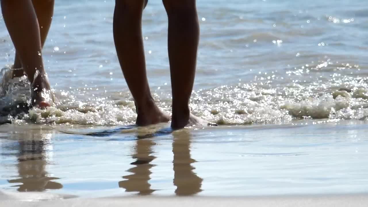 Male and female feet are standing on the sandy beach